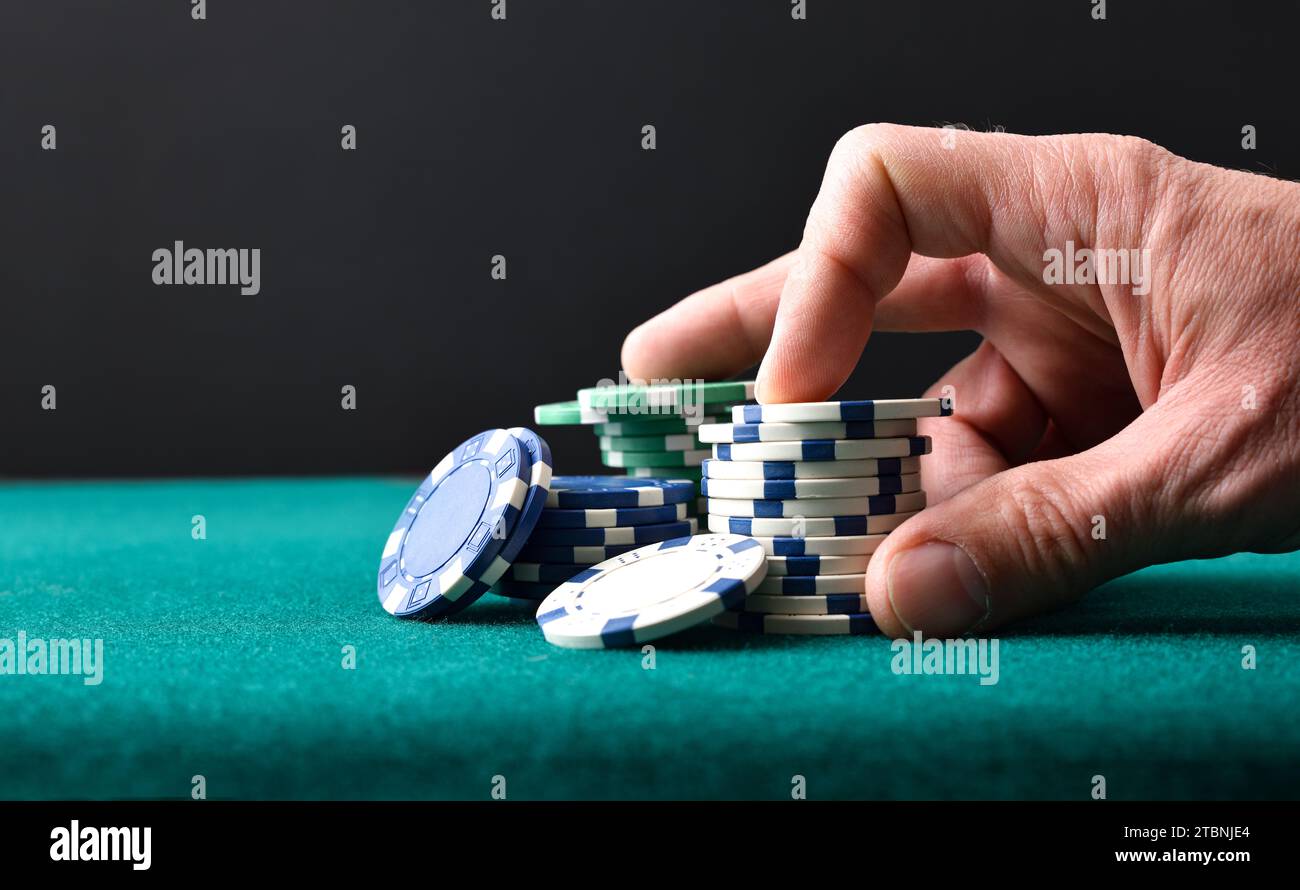 Fond avec jetons de jeu de pari de main sur tapis vert et fond noir isolé. Vue avant. Banque D'Images