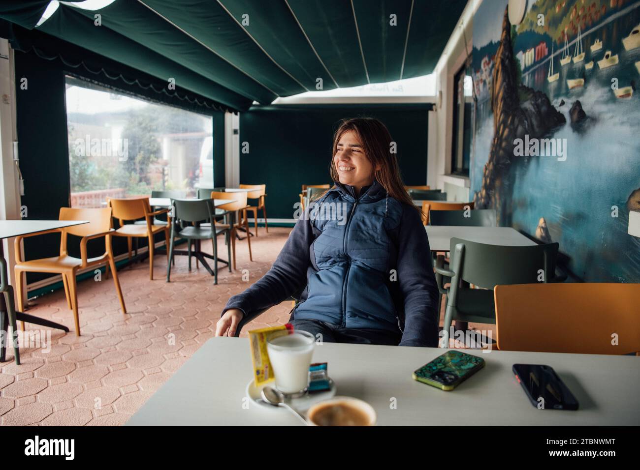Jeune femme profitant du petit déjeuner dans une terrasse Banque D'Images