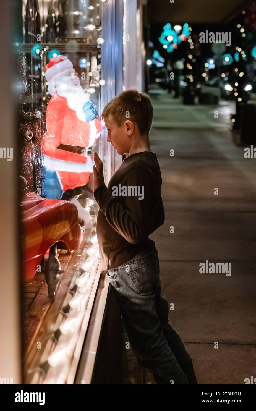 Jeune garçon regardant le camion de pompier jouet dans la vitrine de magasin de Noël Banque D'Images