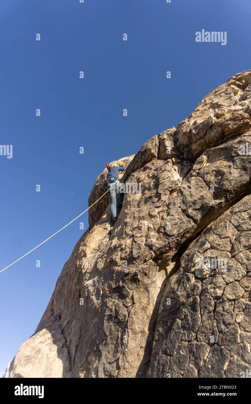 Un homme grimpeur atteint le sommet d'une paroi rocheuse dans Joshua Tree Banque D'Images