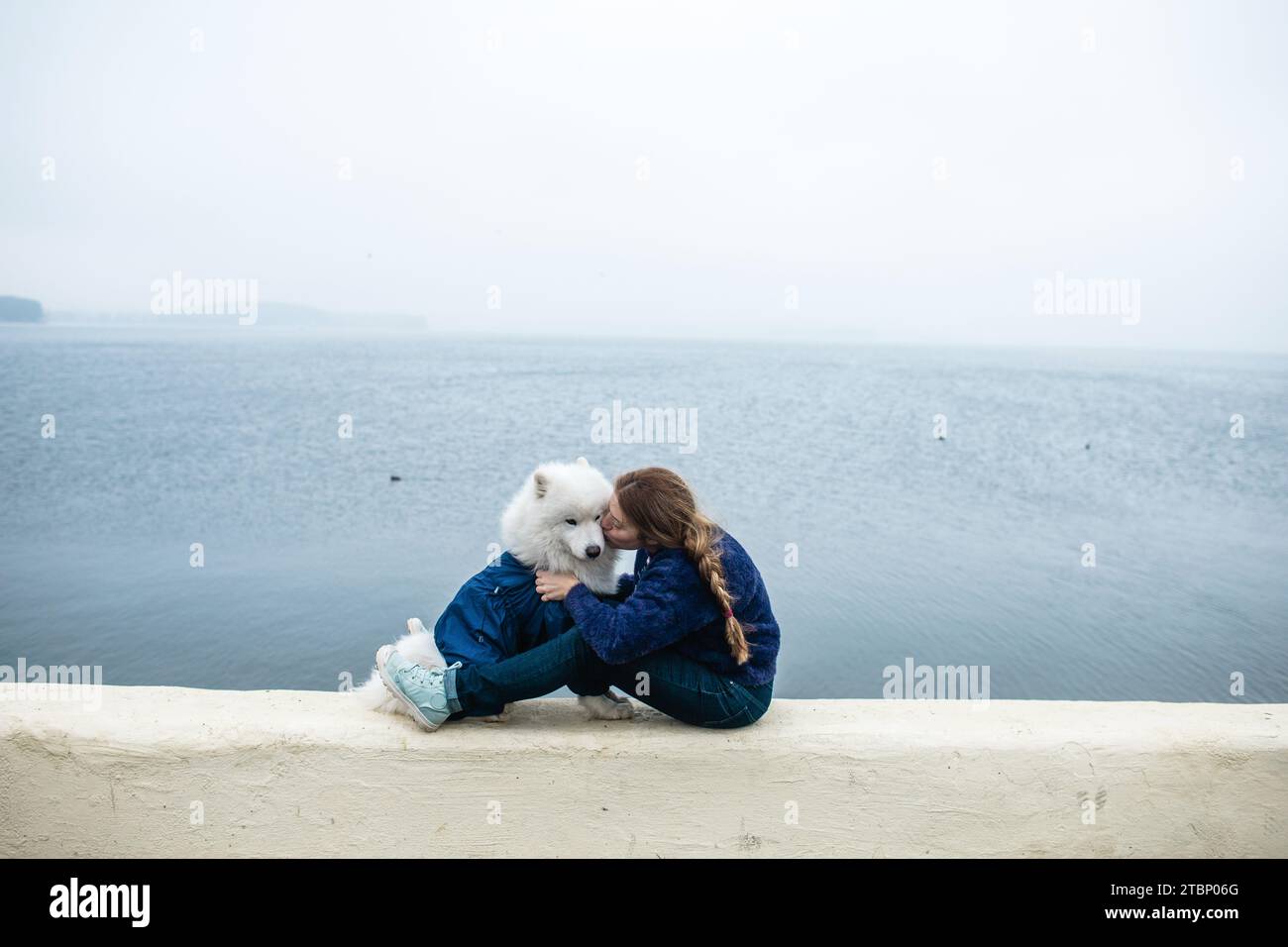 Fille marche avec un chien blanc moelleux Samoyed dans la nature Banque D'Images