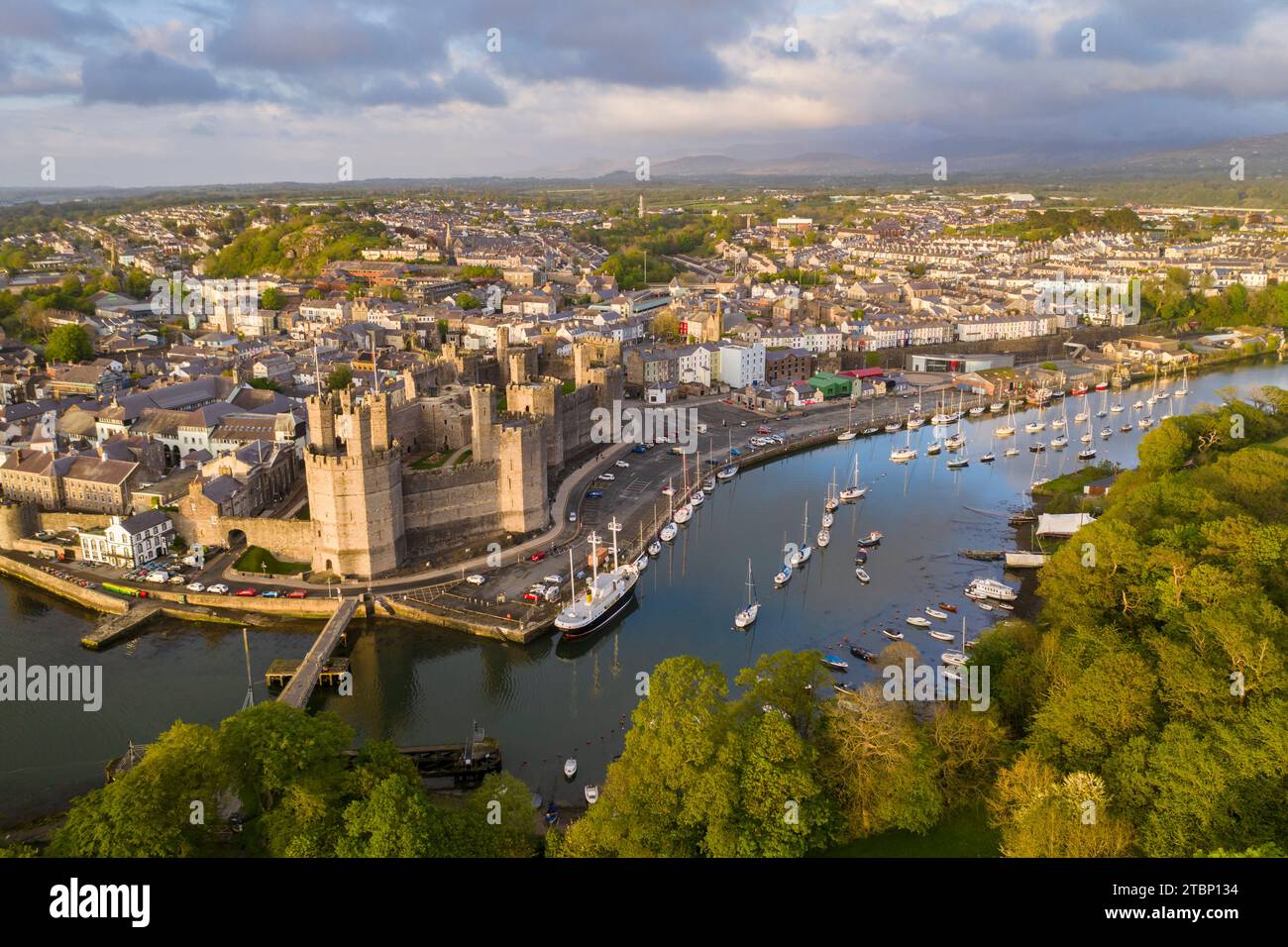 Vue aérienne du château de Caernarfon et de la ville dans la magnifique lumière du soleil du soir, Caernarfon, pays de Galles, Royaume-Uni. Printemps (mai) 2023. Banque D'Images