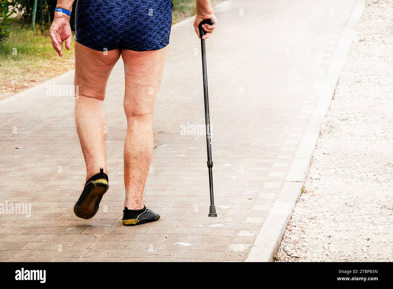 jambes douloureuses d'un homme âgé marchant le long des sentiers de la plage. Prendre soin de la santé articulaire. Banque D'Images