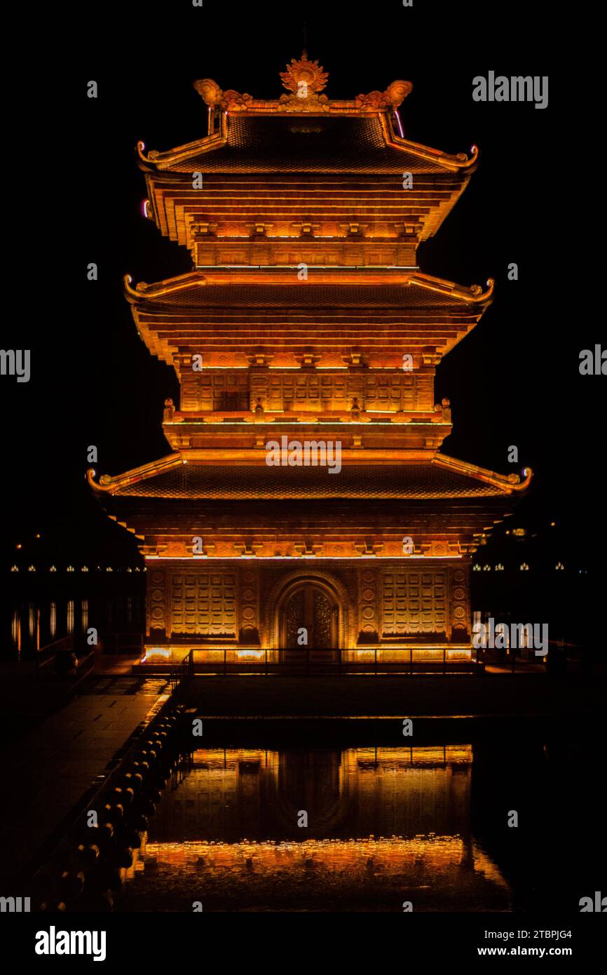 Tour dorée illuminée la nuit au bord de l'eau, Ninh Binh, Vietnam Banque D'Images