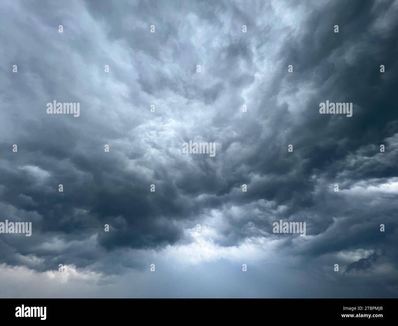 Un ciel sinistre de nuages sombres est vu rouler au-dessus d'une vaste plaine herbeuse, créant une atmosphère dramatique Banque D'Images