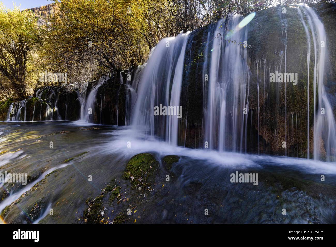 Un paysage magnifique avec une grande cascade descendant dans une rivière entourée d'arbres luxuriants dans un environnement naturel Banque D'Images