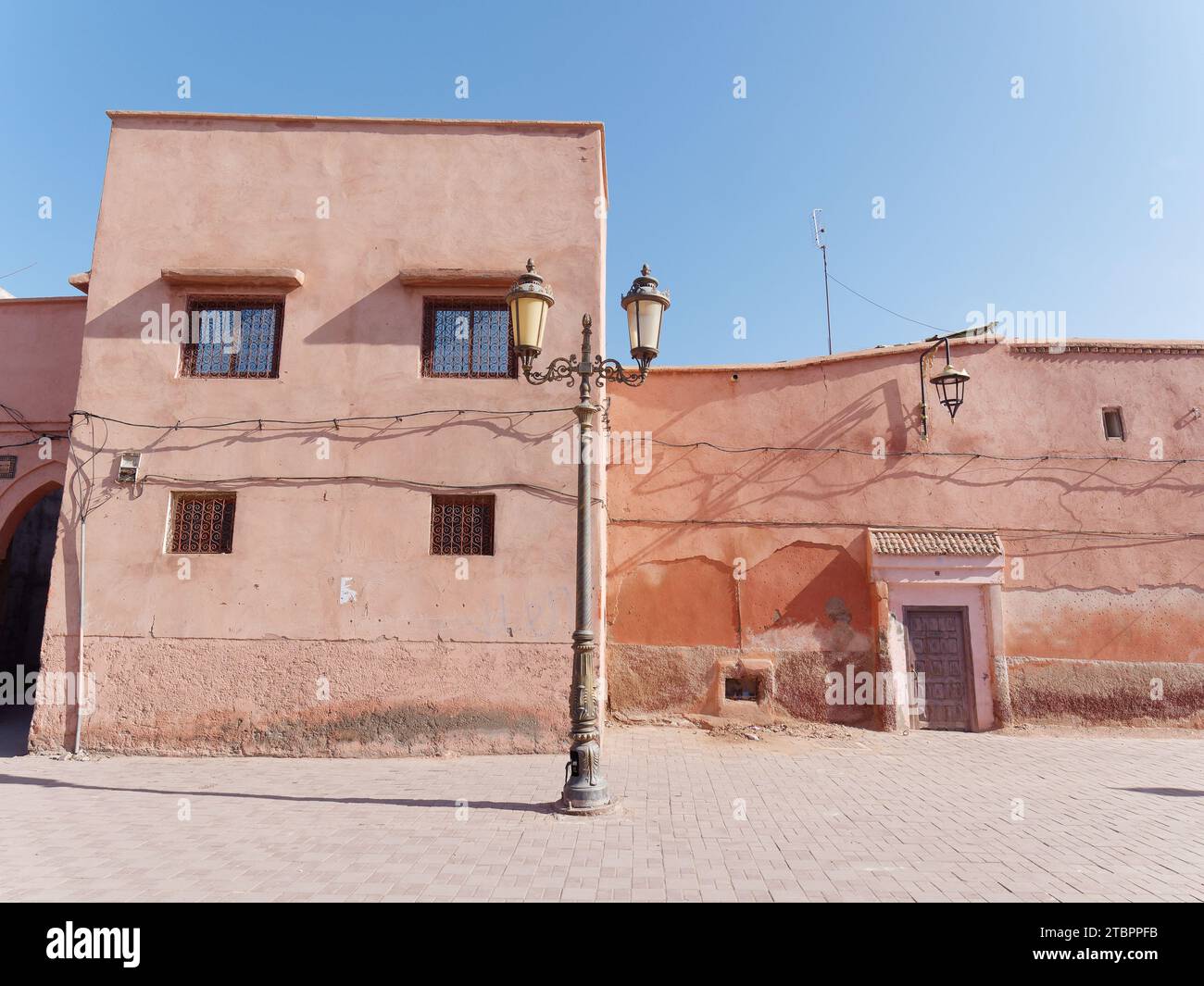 Rue vide avec lampadaire et bâtiment de couleur marron et porte et ciel bleu à Marrakech aka Marrakech, Maroc, 08 décembre 2023 Banque D'Images