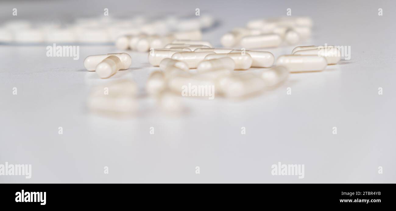 Beaucoup de capsules blanches sont dispersées sur la table. Concept de médicament, pharmacie. Placer pour le texte Banque D'Images