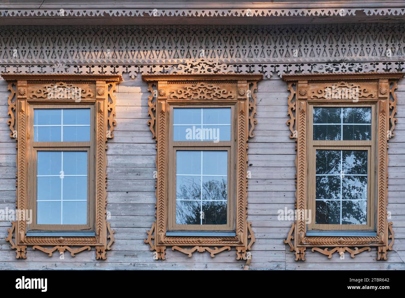Trois fenêtres typiques avec des plateaux en bois sculpté sur le mur de bord de la maison marchande résidentielle du 19e siècle dans le centre historique de la ville Yelabuga, Ru Banque D'Images