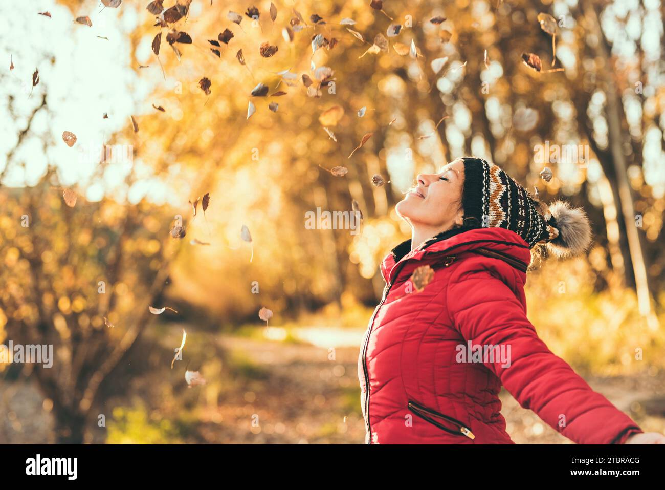 Les gens aiment s'amuser en saison d'automne au parc. Une heureuse femme joyeuse jetant des feuilles en l'air et dépassant ars avec une grande expression de sourire sur le visage. Mode de vie naturel dame profiter de la vie Banque D'Images