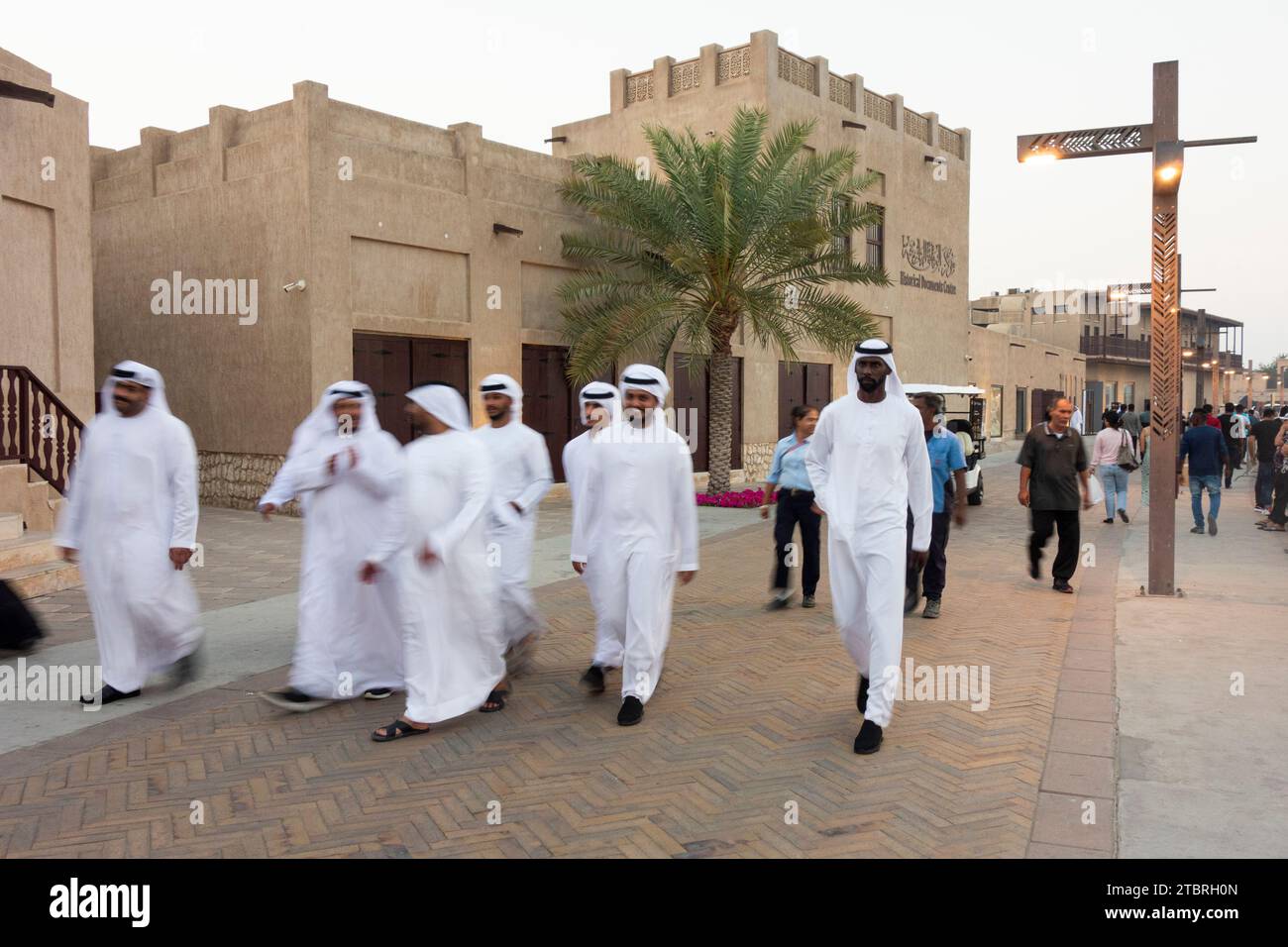 Un petit groupe d'hommes émiratis marchent à travers le quartier du patrimoine Al Shindagha au crépuscule, Dubaï, Émirats arabes Unis. Banque D'Images