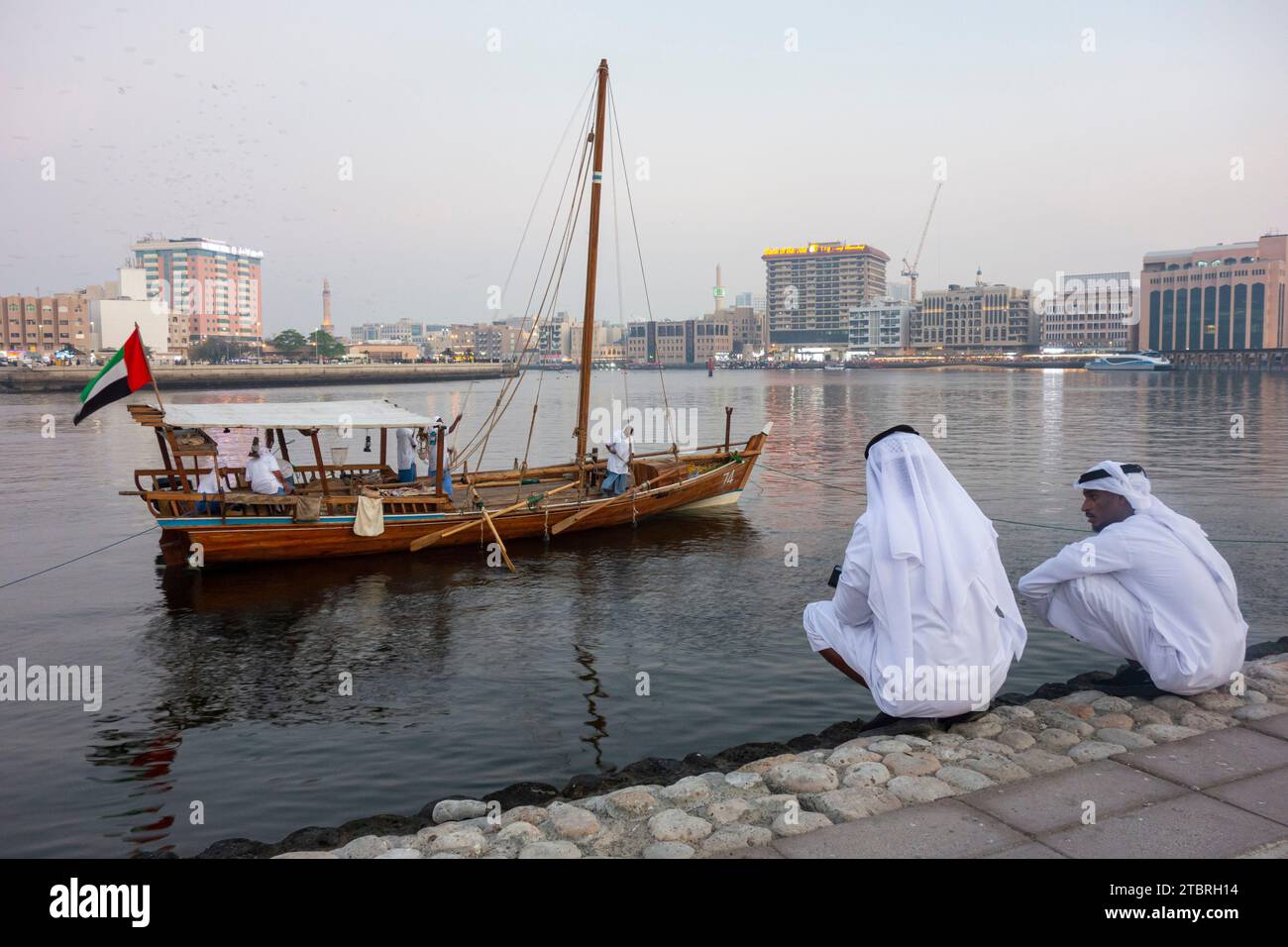 Deux hommes locaux accroupissent sur le rivage du ruisseau dans le quartier historique d'Al Shindagha, Dubaï, Émirats arabes Unis. Banque D'Images