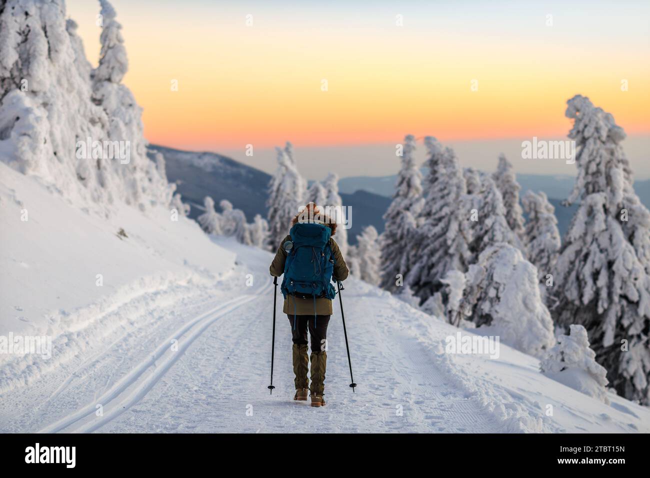 Femme randonnée dans la neige sur le sentier de trekking dans les montagnes d'hiver au coucher du soleil. Sports et activités de plein air saisonnières Banque D'Images
