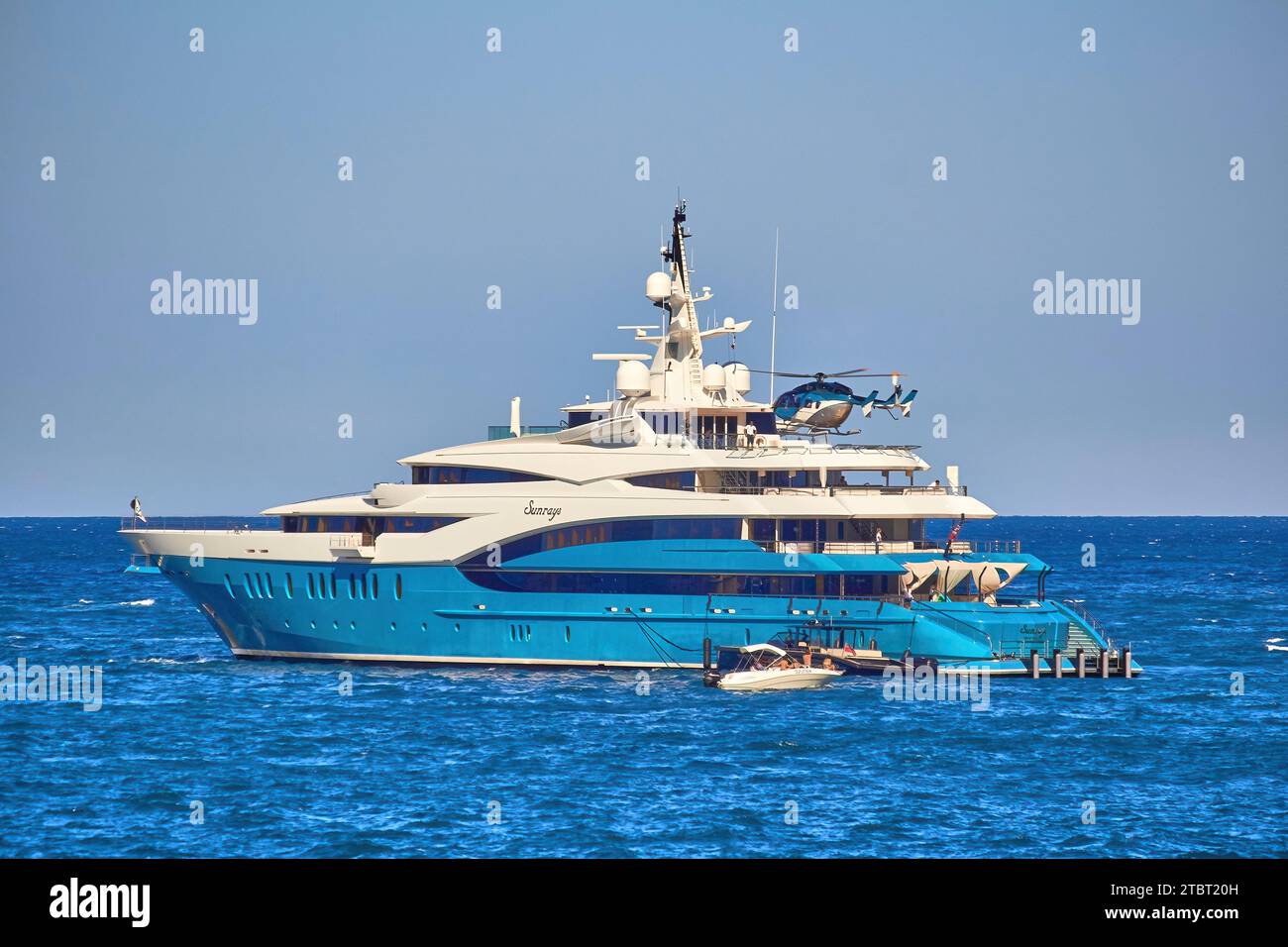 Rayons de soleil de superyacht de 85m à l'ancre avec l'hélicoptère entrant pour atterrir sur l'hélideck. Banque D'Images