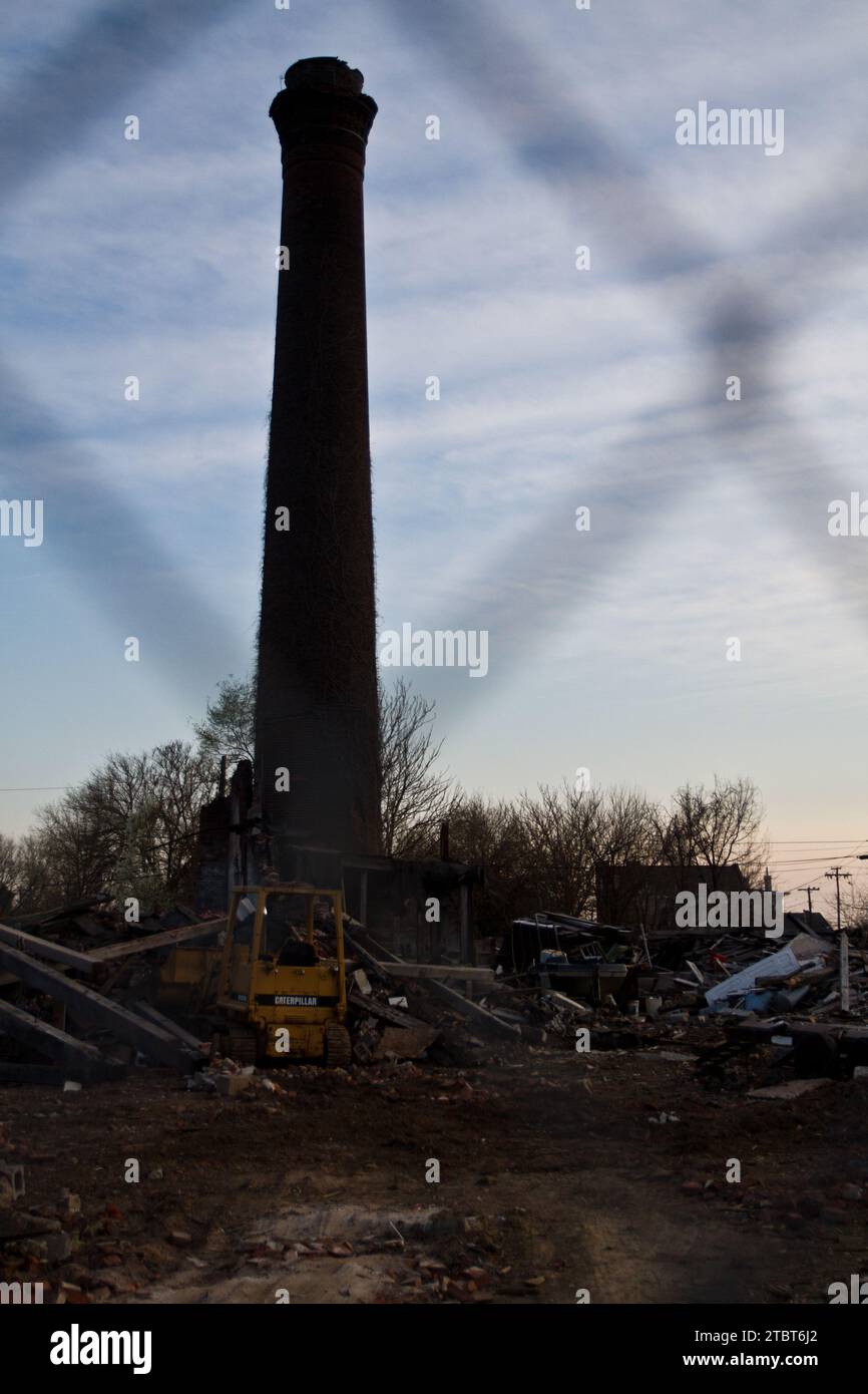 Démolition crépusculaire de l'ère industrielle avec Siloh géant à travers la clôture Banque D'Images