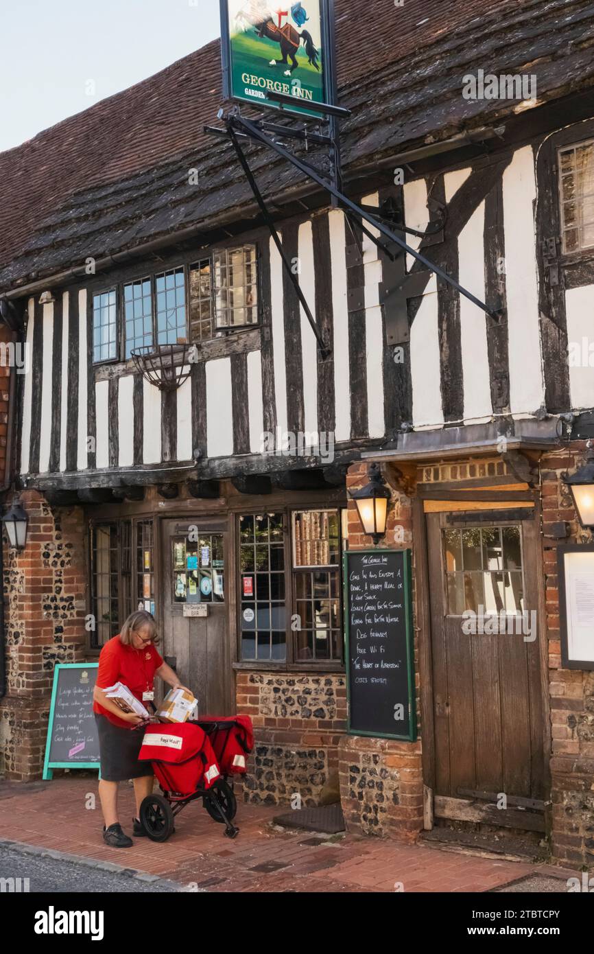 Angleterre, East Sussex, Alfriston, Alfriston Village, scène de rue avec une employée de poste livrant le courrier Banque D'Images