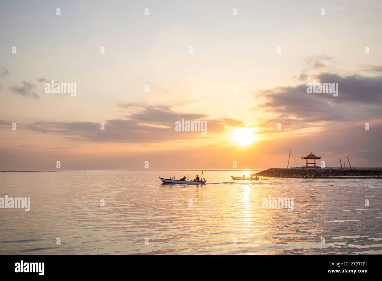 Paysage matinal pris sur une plage de sable, vue sur la mer à l'horizon avec de petits temples dans l'eau et un jukung, un bateau de pêche traditionnel dans la mer, lever du soleil à Sanur, Bali, Indonésie Banque D'Images