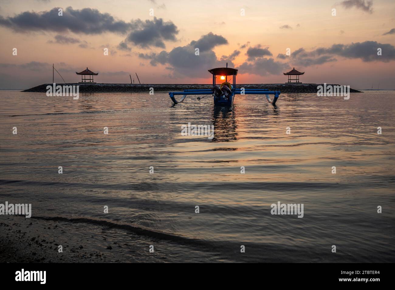 Paysage matinal pris sur une plage de sable, vue sur la mer à l'horizon avec de petits temples dans l'eau et un jukung, un bateau de pêche traditionnel dans la mer, lever du soleil à Sanur, Bali, Indonésie Banque D'Images