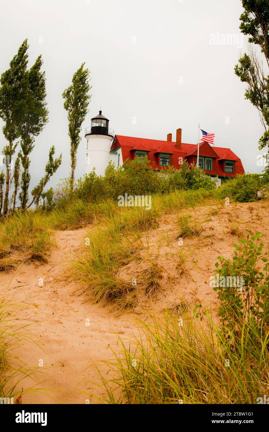 Phare blanc classique avec toit rouge sous ciel couvert dans les dunes de sable Banque D'Images