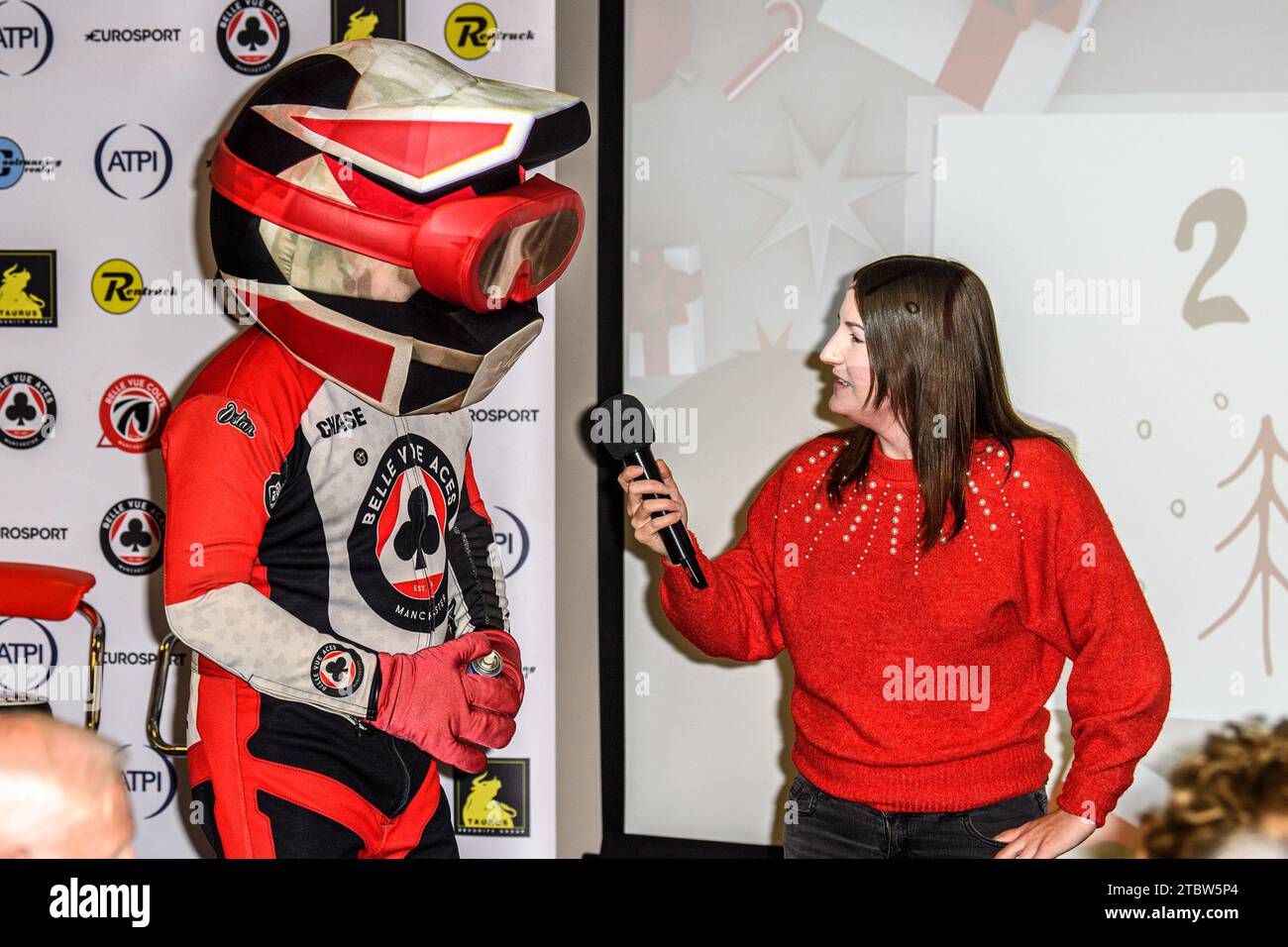 La mascotte Belle vue Chase the Ace (à gauche) est « interviewée » par Hayley Bromley, présentatrice de Belle vue Meeting, lors de l’annonce de l’équipe Cracker 2024 de Belle vue Speedway dans la suite Peter Craven du National Speedway Stadium, Manchester, le vendredi 8 décembre 2023. (Photo : Ian Charles | MI News) crédit : MI News & Sport / Alamy Live News Banque D'Images