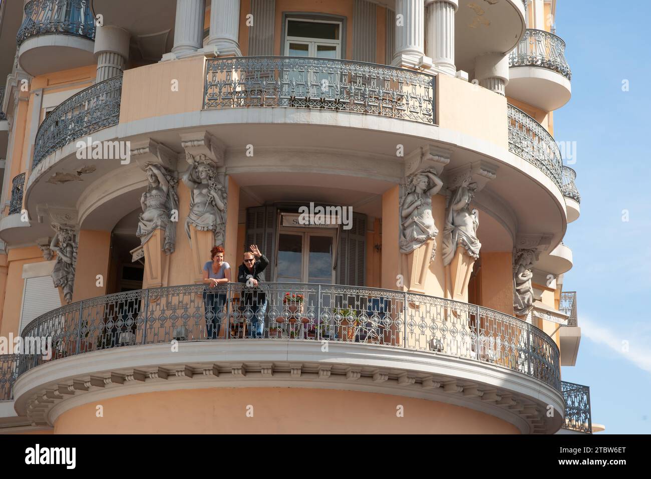 Cannes, Côte d'Azur.- Mai 3 2011 ; couple agitant et s'appuyant sur la balustrade d'un bâtiment traditionnel de style Belle-Epoche. Banque D'Images