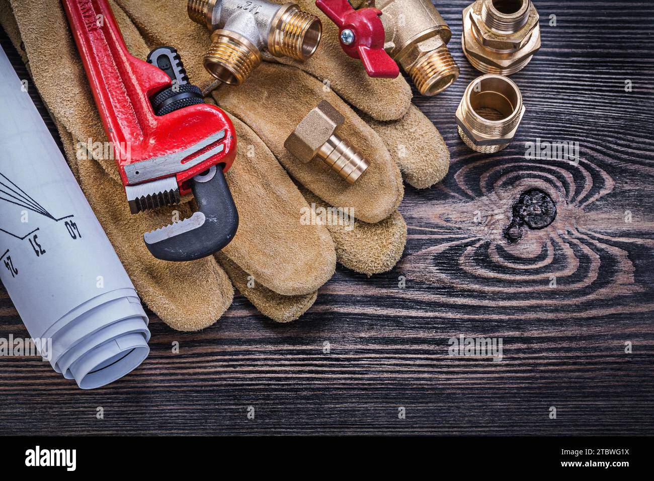 Gants de protection en cuir construction de clé singe plans en laiton plomberie robinetterie vanne sur planche de bois Banque D'Images