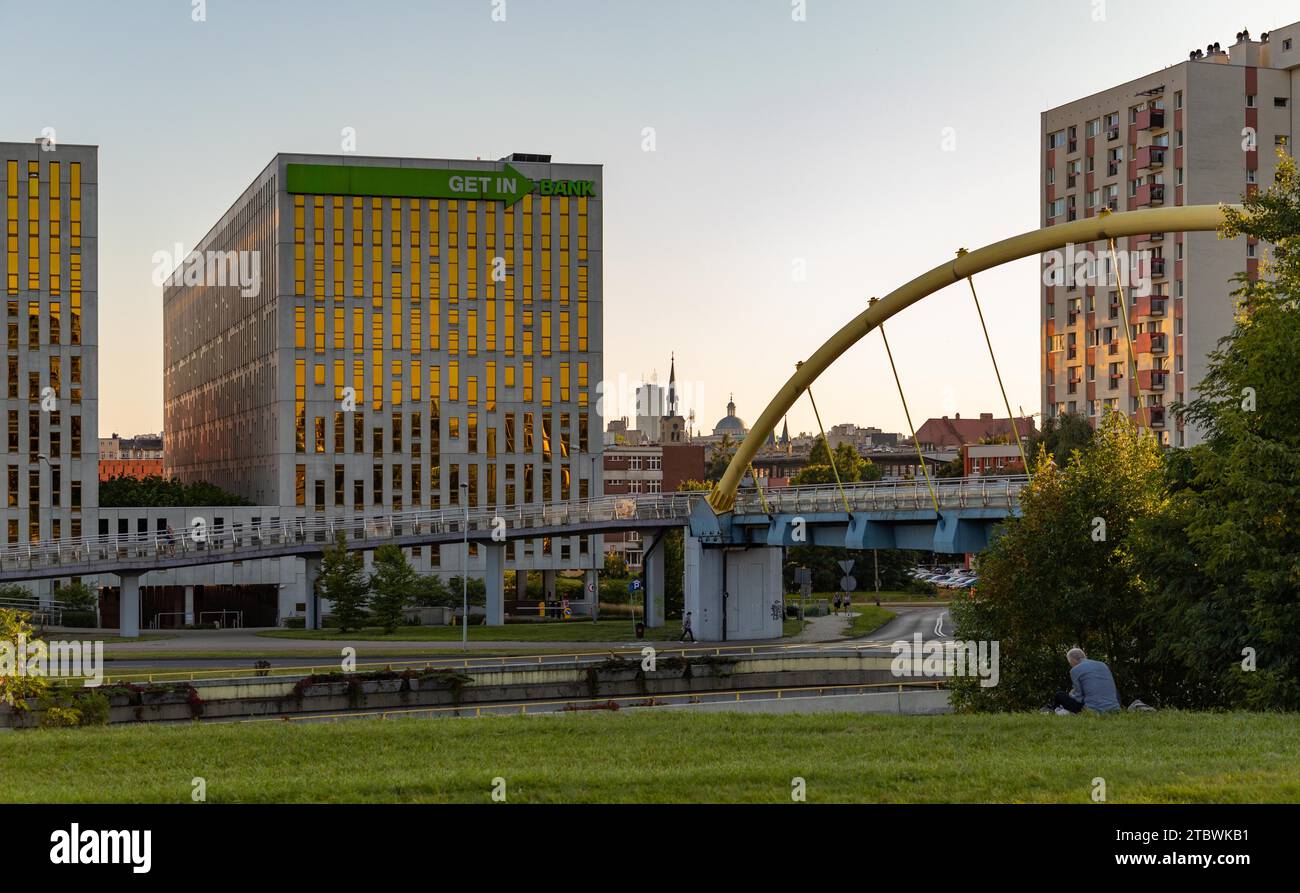 Une photo de l'avenue RO?dzie?skiego, le pont piétonnier, les bâtiments autour et un homme assis sur l'herbe Banque D'Images