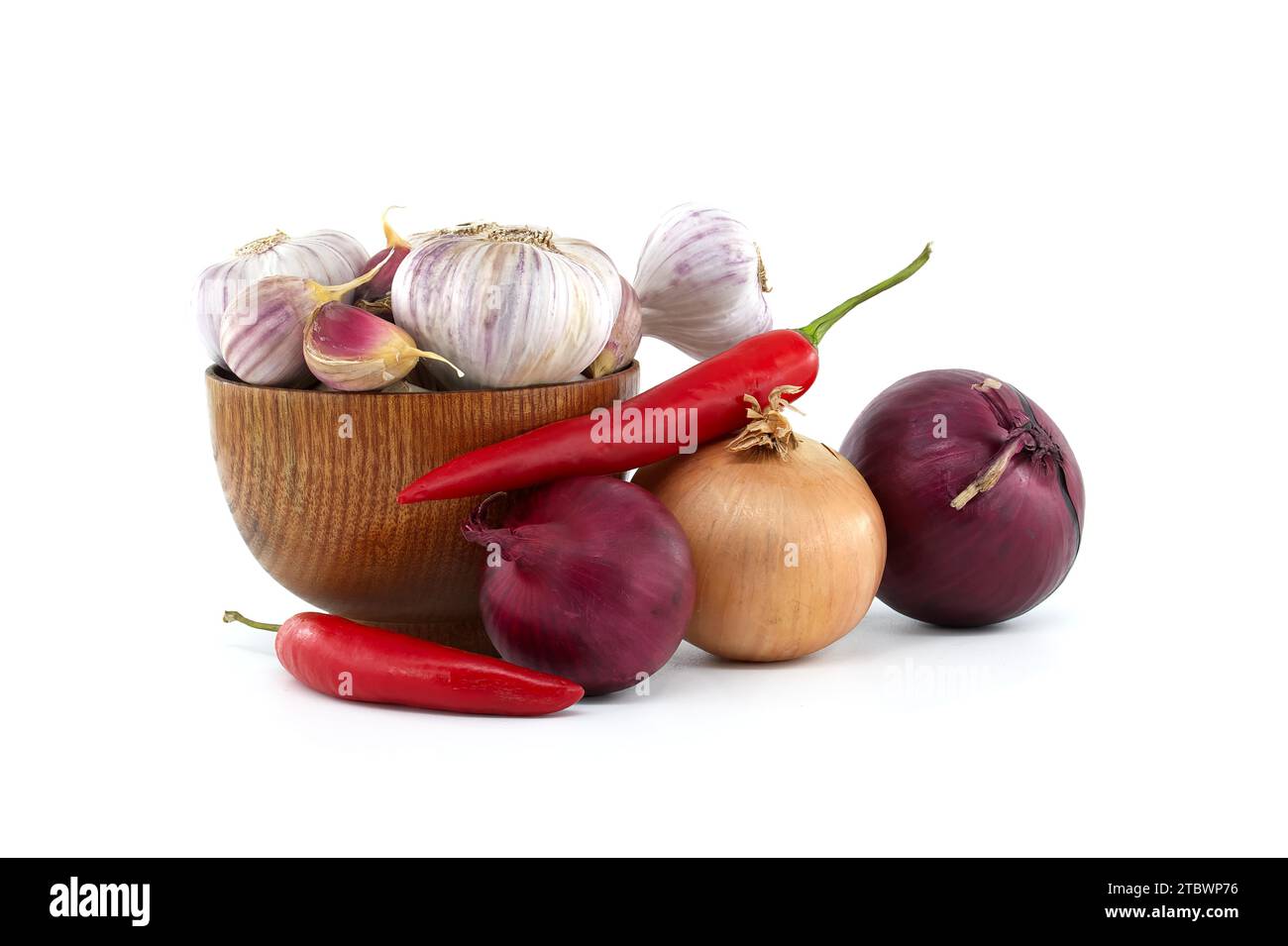 Bulbes et gousses d'ail dans un bol en bois près du piment rouge, oignon rouge et jaune isolé sur fond blanc Banque D'Images