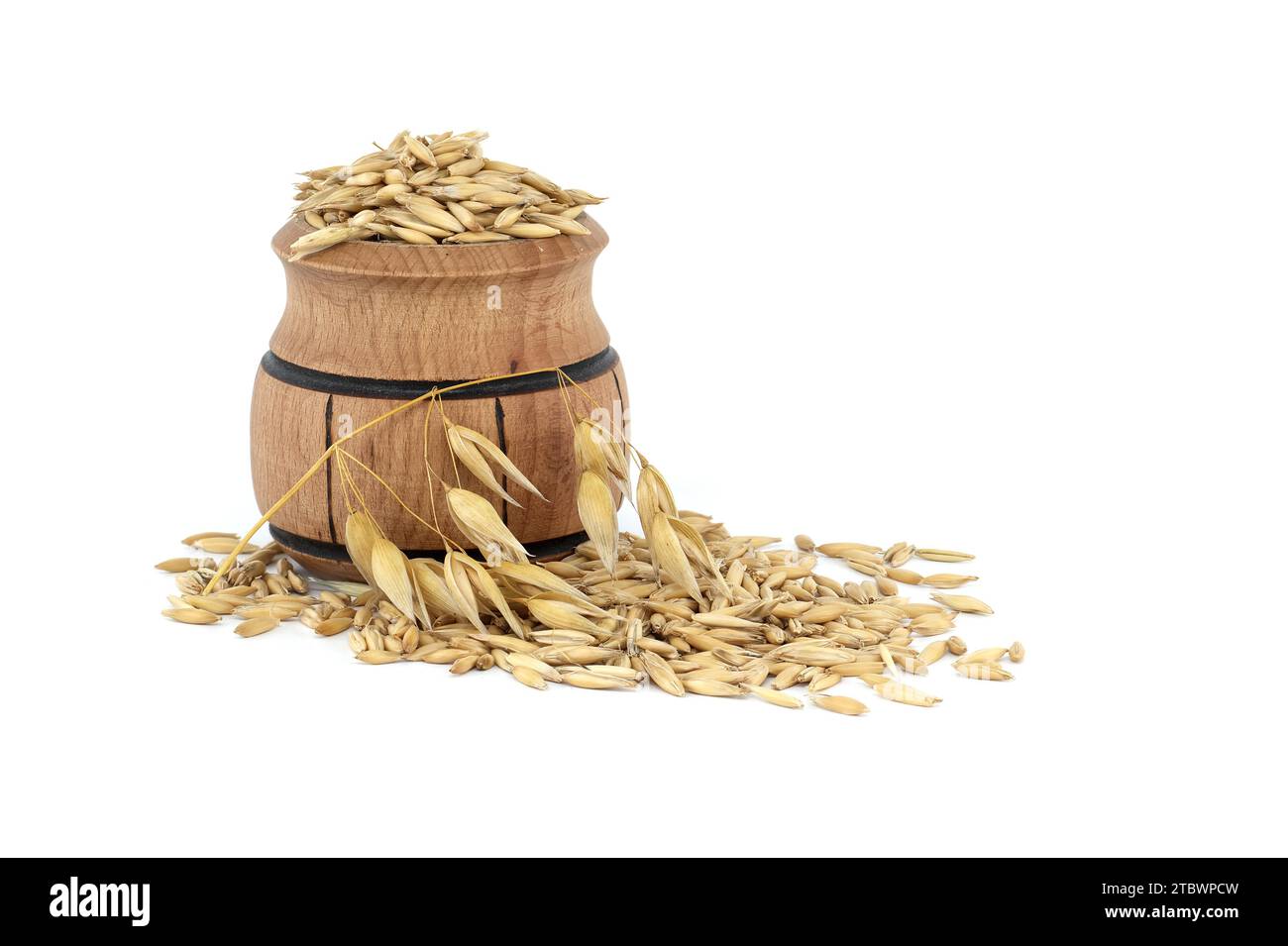 Tas de grains d'avoine biologique avec des coques ou des enveloppes dans un petit tonneau en bois isolé sur fond blanc. Grains d'avoine entiers avec enveloppe. Agriculture, alimentation Banque D'Images