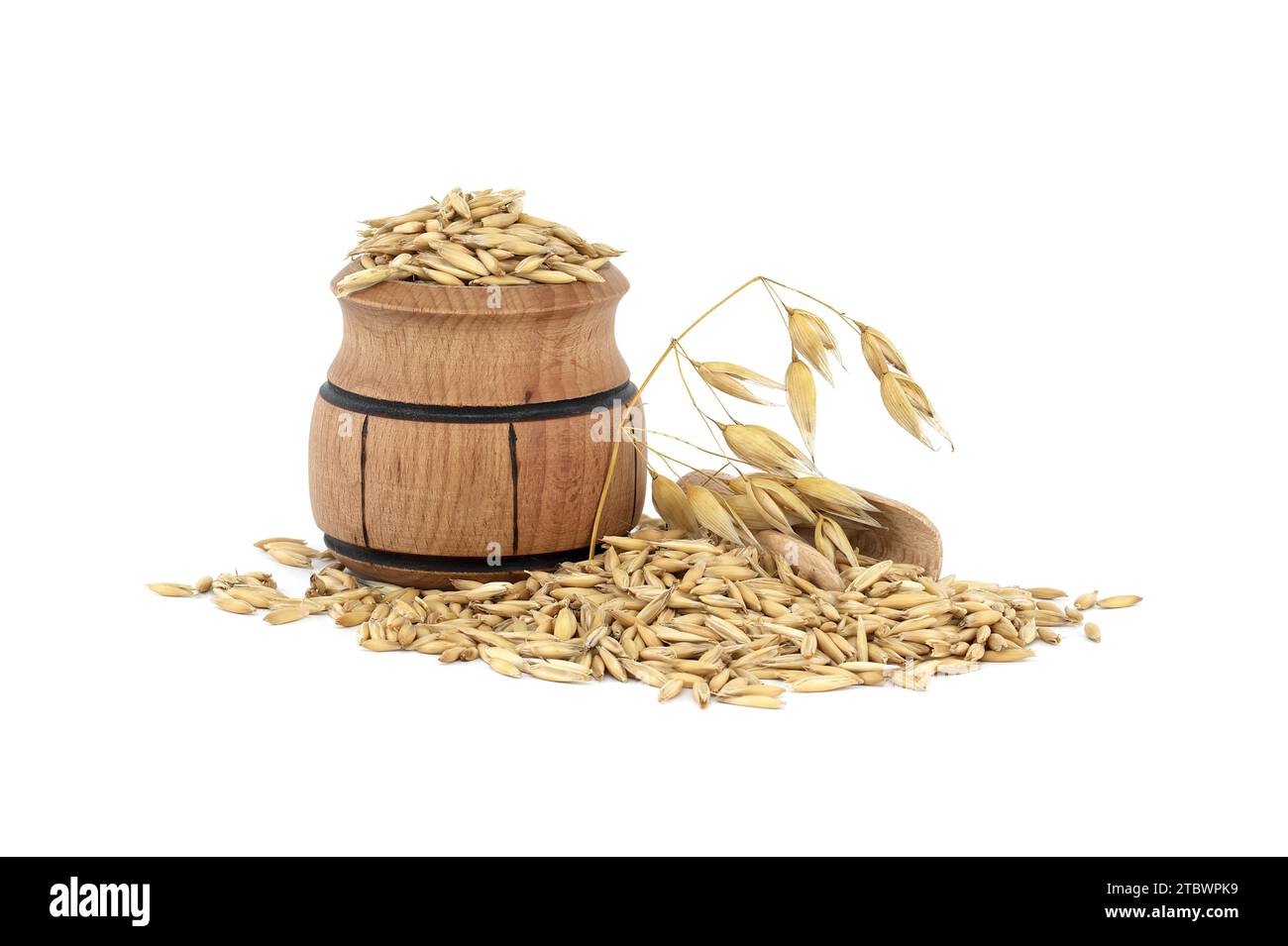 Tas de grains d'avoine biologique avec des coques ou des enveloppes dans un petit tonneau en bois isolé sur fond blanc. Grains d'avoine entiers avec enveloppe. Agriculture, alimentation Banque D'Images