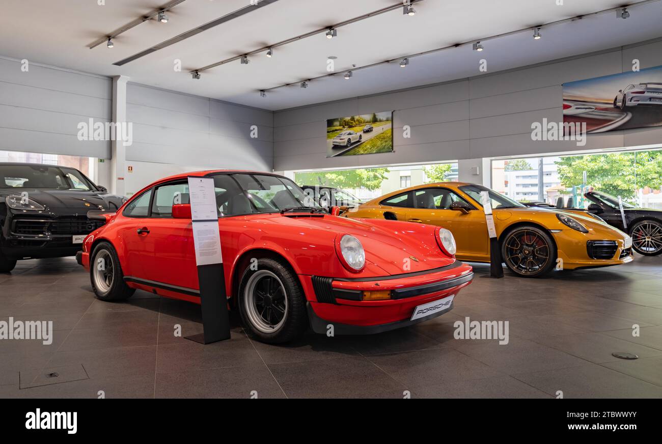 Une photo d'une Porsche 911 Carrera 3,0 rouge à côté d'une Porsche 911 Turbo S orange à l'intérieur d'une concession Banque D'Images