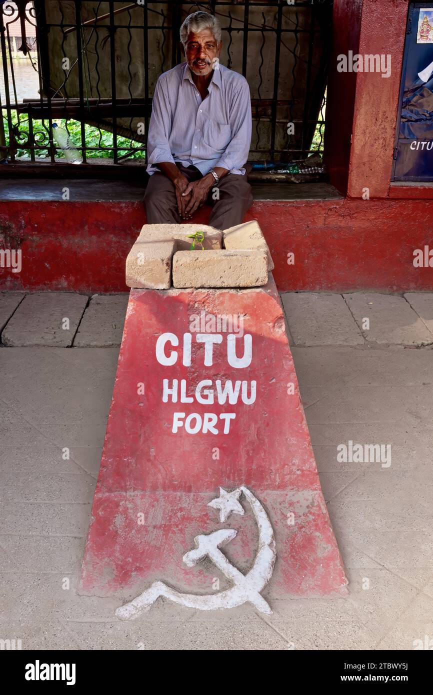 Un homme est assis près d'un marqueur de pierre avec l'inscription CITU (Centre des syndicats) et le symbole communiste du marteau et de la faucille ; Trivandrum, Kerala Inde Banque D'Images