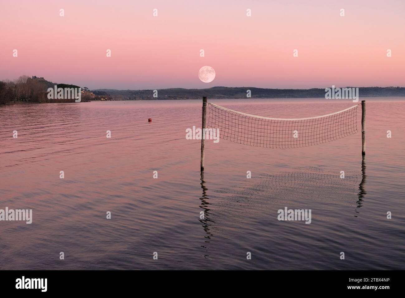 Filet de volley-ball debout dans l'eau du lac avec la pleine lune en arrière-plan Banque D'Images