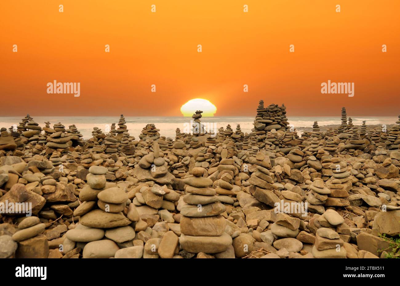 Pierres zen, pyramides de roche empilées sur la plage de galets au coucher du soleil. Banque D'Images