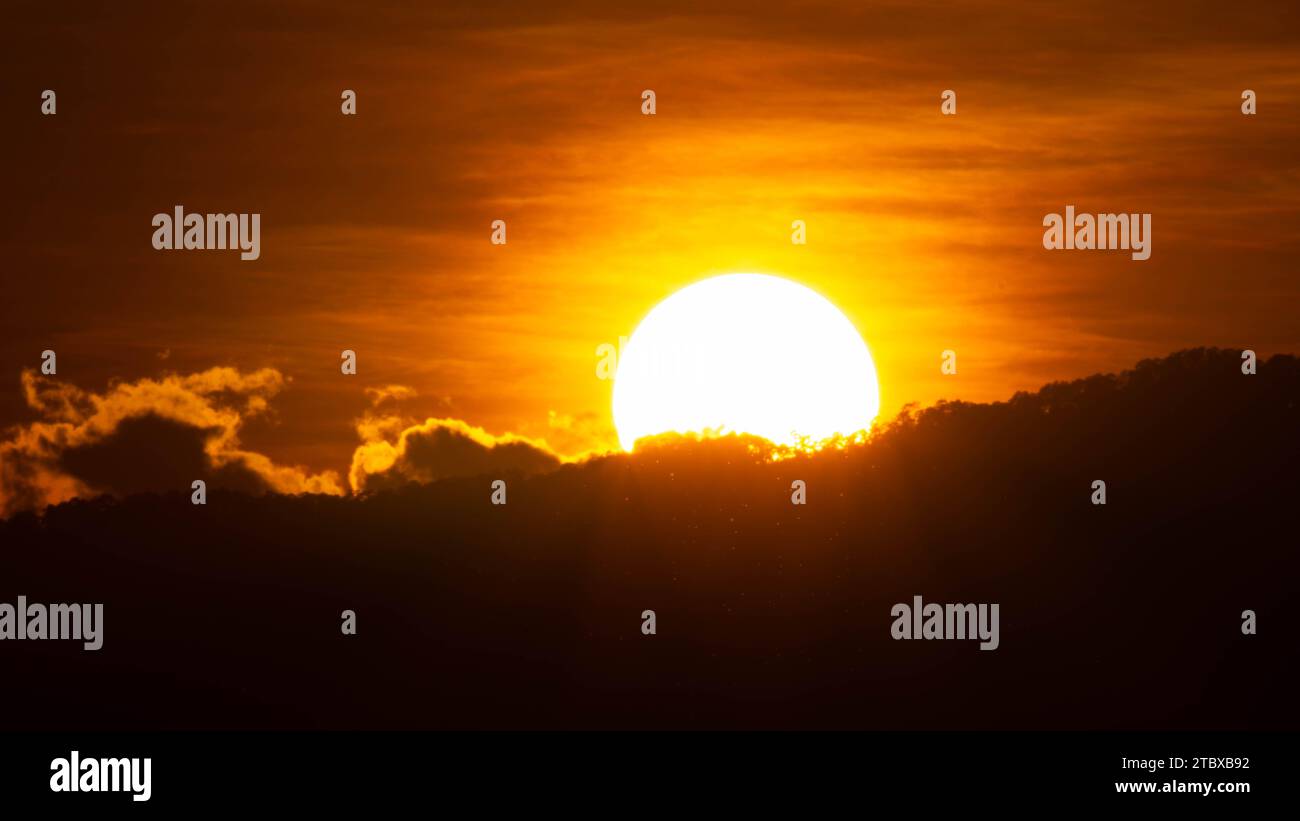 Gros plan de grand soleil lumineux sur le ciel avec des couleurs dégradés orange dans une soirée calme. Banque D'Images