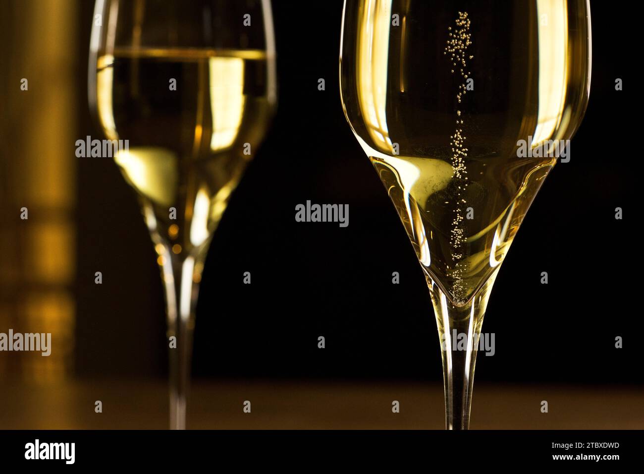 Champagne pétillant dans un verre dans une salle de fête sombre - gros plan Banque D'Images