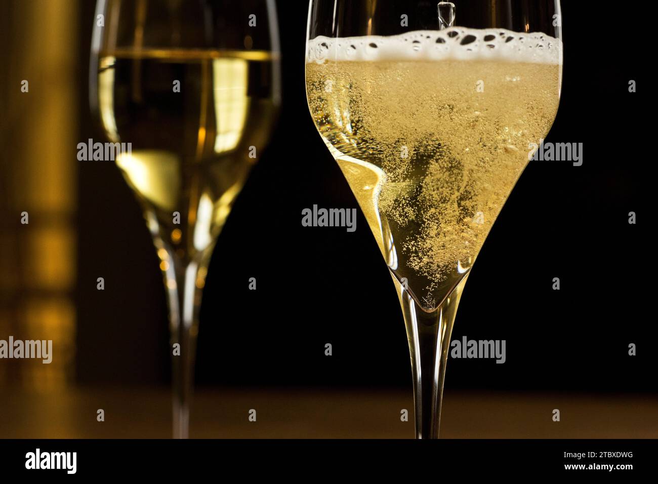 Champagne pétillant dans un verre dans une salle de fête sombre - gros plan Banque D'Images