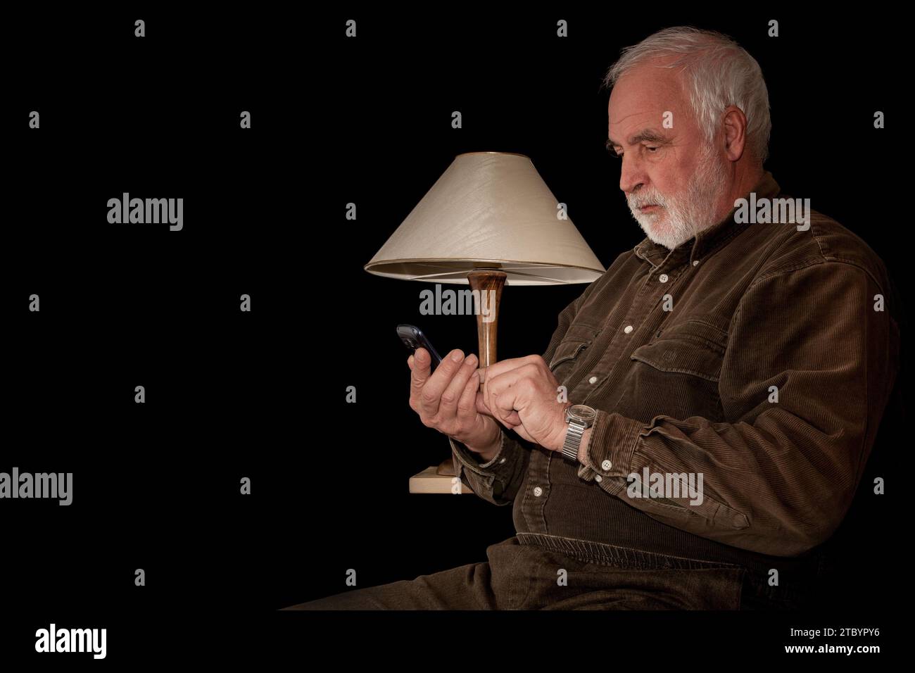 Seul, entouré de silence, un vieil homme et son smartphone - son pont vers le monde. Proximité virtuelle et pourtant solitude. Banque D'Images