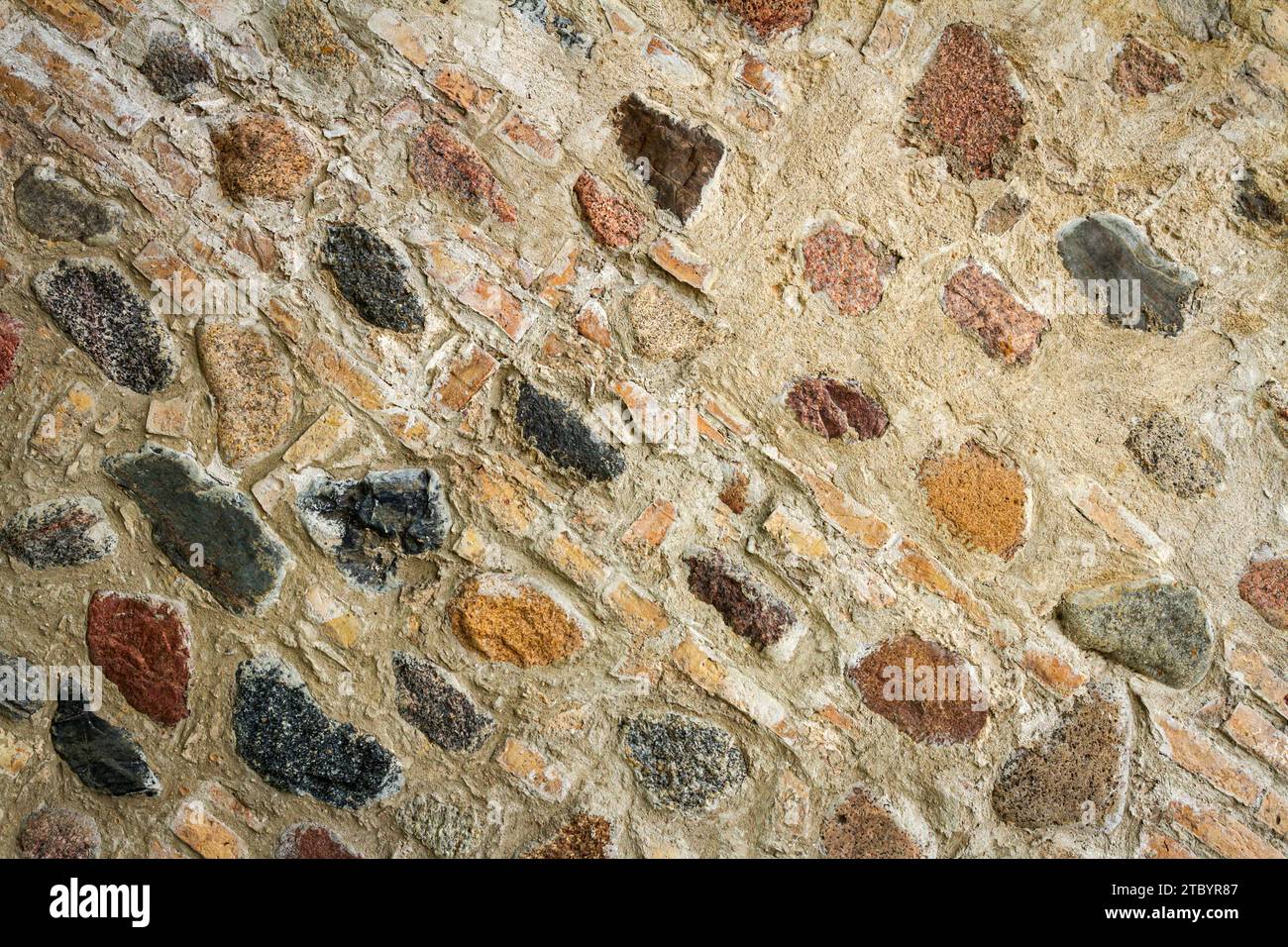 Texture du mur avec des morceaux de vieilles briques mélangées avec des pierres rondes apparentes. Fond de brique et texture de mur de pierre. Banque D'Images