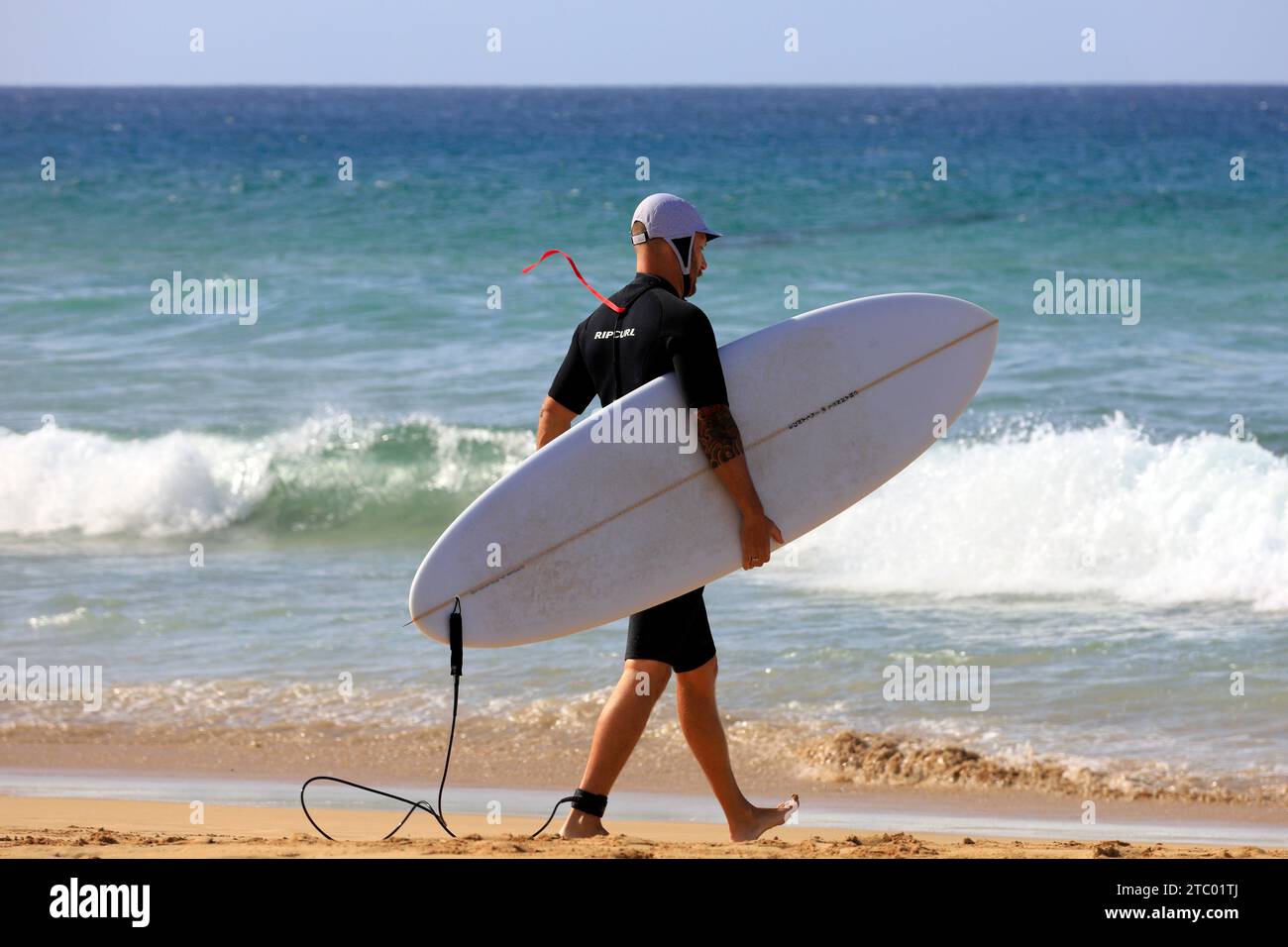 Homme portant planche de surf marchant vers la mer, El Cotillo, Fuerteventura, Îles Canaries, Espagne. Prise en novembre 2023. cym Banque D'Images