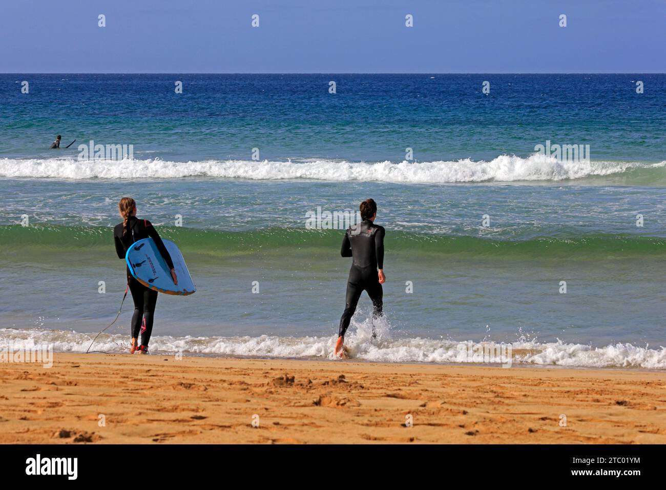 Homme et femme en combinaison avec planche de surf marchant vers la mer, El Cotillo, Fuerteventura, Îles Canaries, Espagne. Prise en novembre 2023 Banque D'Images
