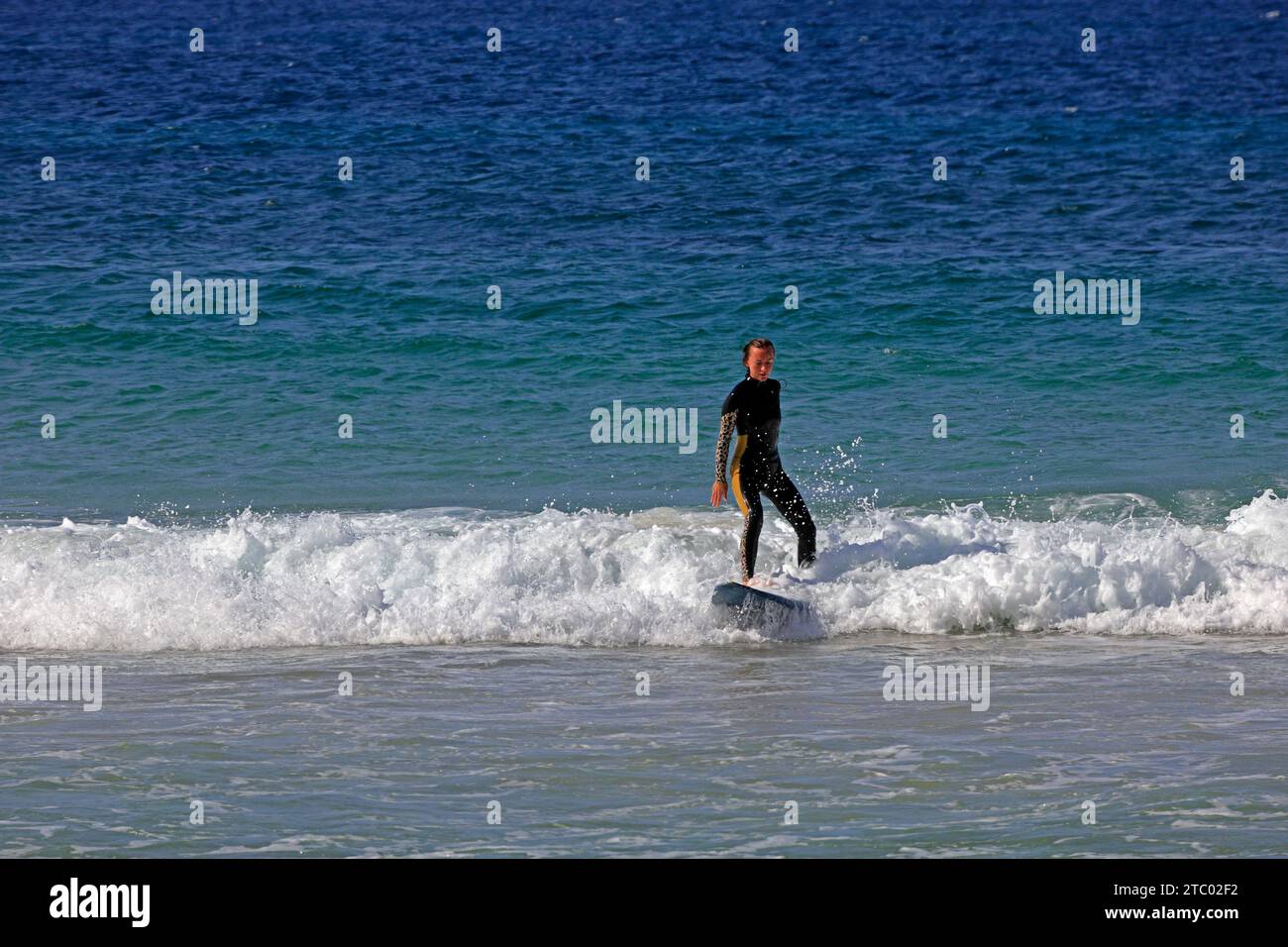 Femme surfant à Piedra Beach, debout sur une planche de surf, El Cotillo, Fuerteventura, Îles Canaries, Espagne. Prise en novembre 2023 Banque D'Images