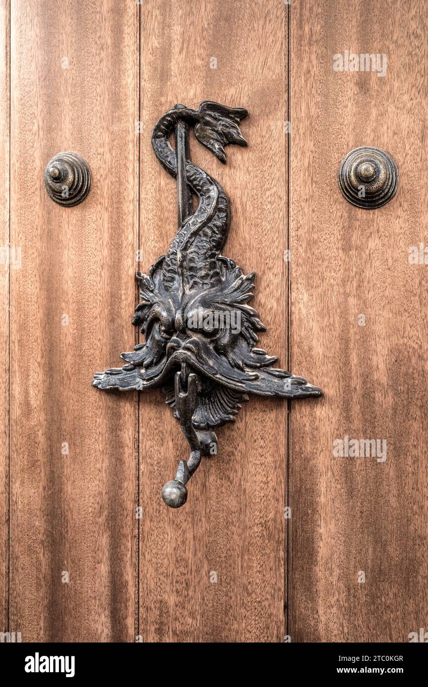 Heurtoir artistique de porte en bois d'une tête, visage et queue enroulés autour d'un bâton dans le village de Villafames (Vilafames), Castellon (Castello), Espagne. Banque D'Images