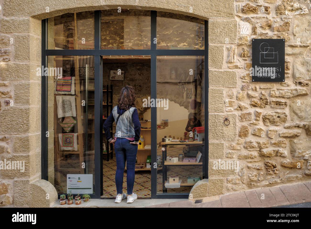 Femme à la porte d'un magasin de petites choses et de détails regardant comment l'artiste travaille dans la ville de Culla, l'une des plus belles d'Espagne. Banque D'Images