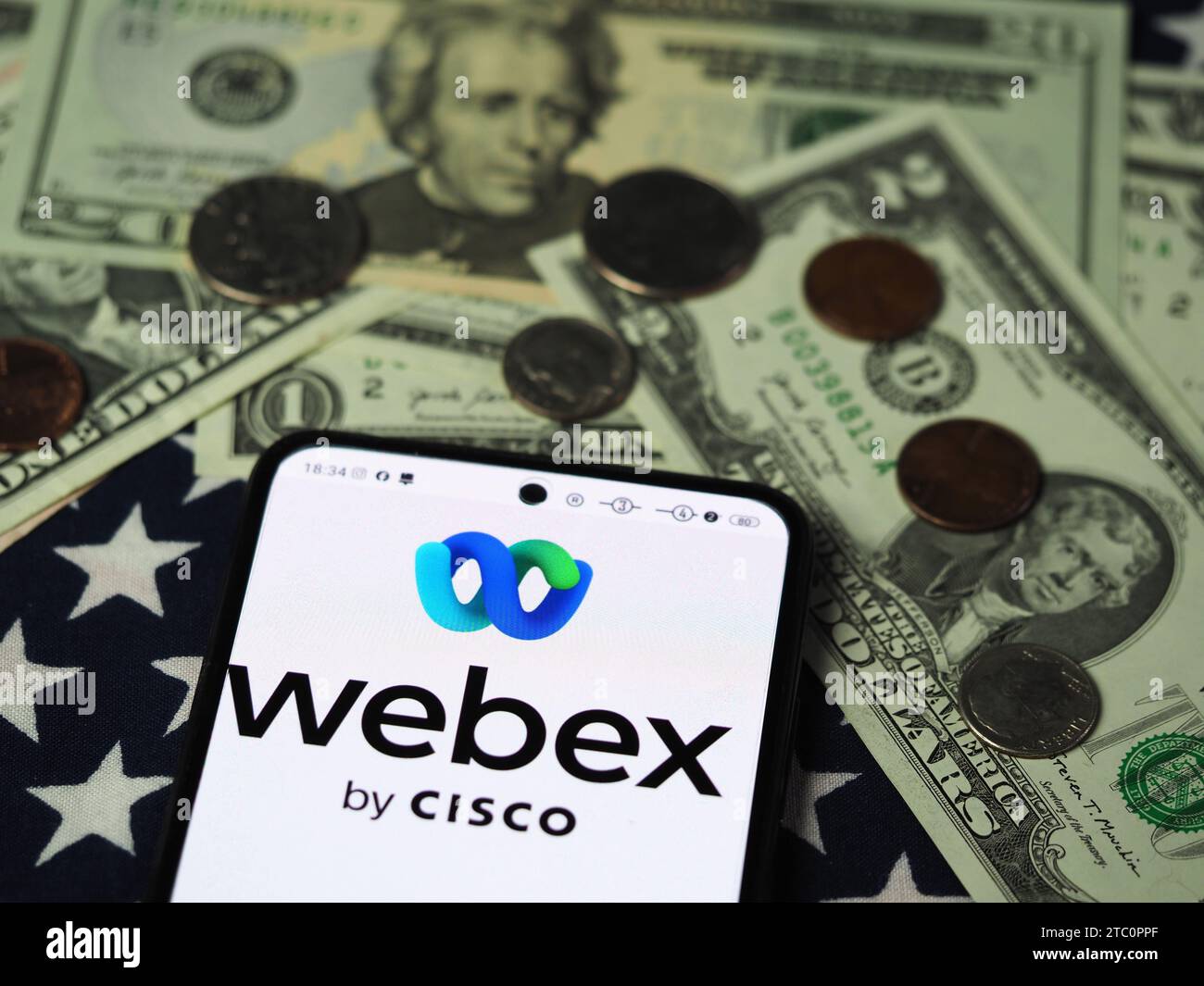 Dans cette illustration photo, un logo Webex by Cisco est affiché sur un smartphone avec des billets et des pièces de monnaie en dollars américains en arrière-plan. Banque D'Images