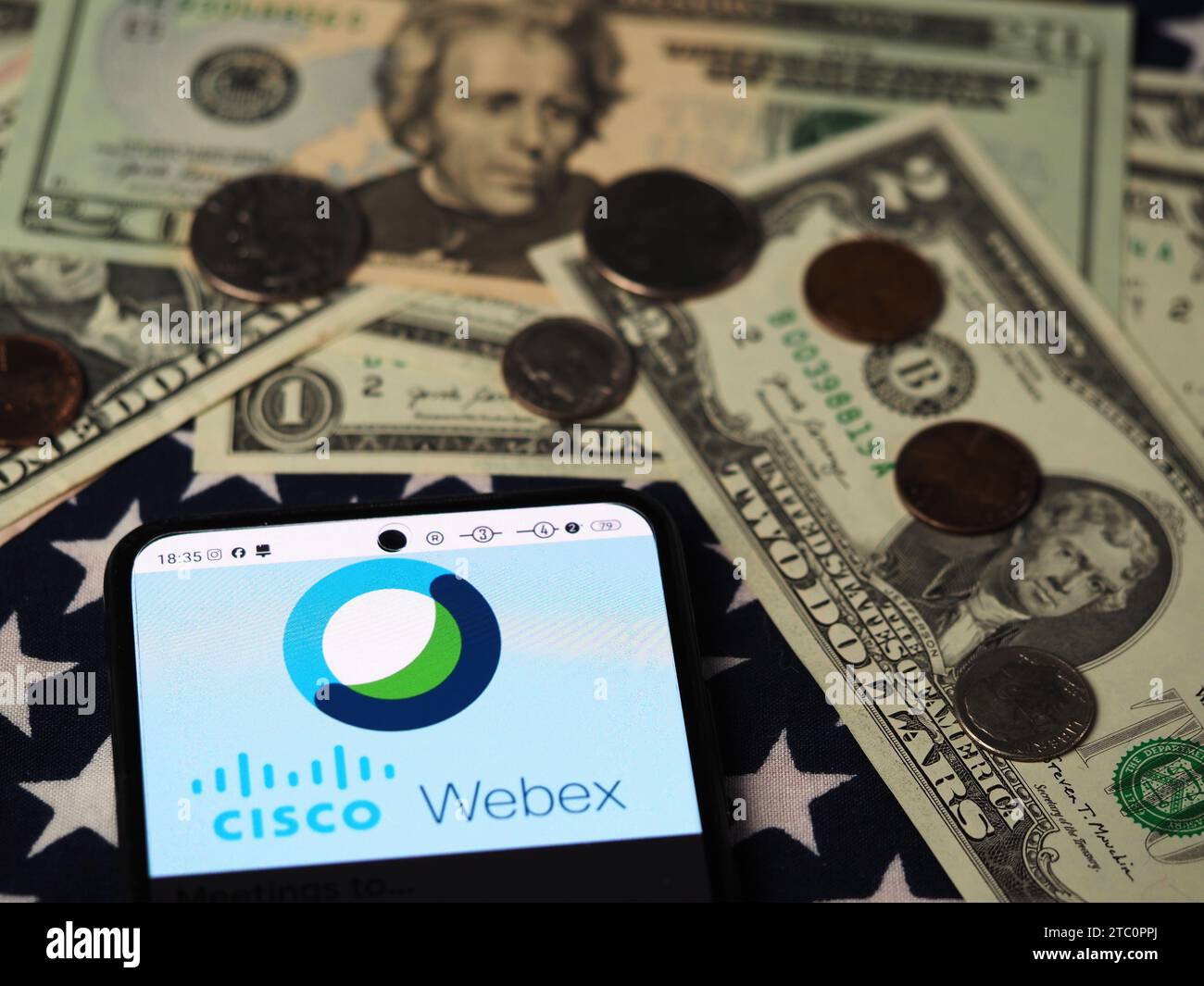 Dans cette illustration photo, un logo Webex by Cisco est affiché sur un smartphone avec des billets et des pièces de monnaie en dollars américains en arrière-plan. Banque D'Images