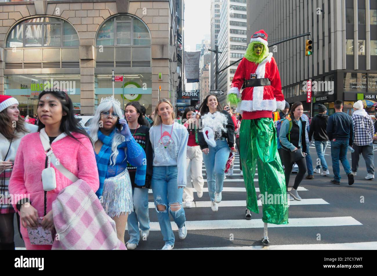 New York, États-Unis. 09 décembre 2023. Un participant de SantaCon portant un costume de Grinch traverse la rue. Les fêtards habillés en Père Noël ou autres personnages de Noël se sont réunis à Manhattan, New York City pour SantaCon, une tournée annuelle autour du thème de Noël qui collecte des fonds pour des œuvres caritatives. Les donateurs ont reçu des entrées dans les lieux participants, tels que les bars et les clubs. (Photo de Jimin Kim/SOPA Images/Sipa USA) crédit : SIPA USA/Alamy Live News Banque D'Images