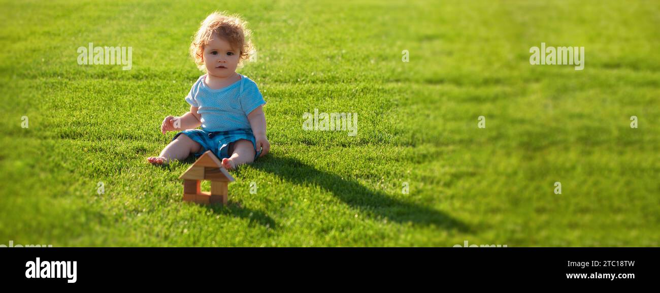 Bannière avec tête de ressort pour enfant.Assurance enfants.Bébé joue dans l'herbe verte.Temps de printemps chaud dans le parc. Banque D'Images
