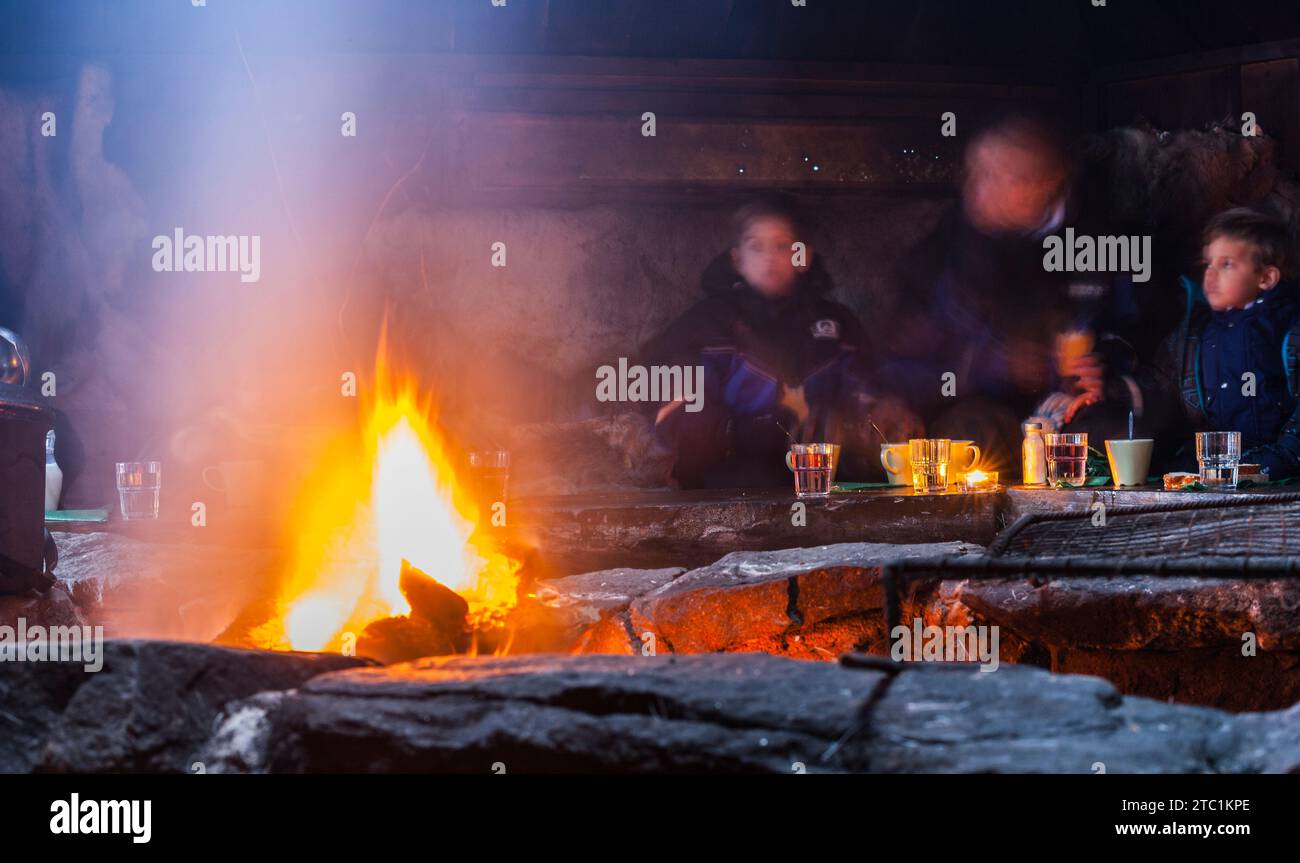 Saariselka, Finlande - 29 novembre 2010. Famille dans un Sami 'kota'. Le kota (ou goahti), est une cabane ou tente Sami. Il a une cheminée dans le centre et Banque D'Images Saariselka, Finlande - 29 novembre 2010. Famille dans un Sami 'kota'. Le kota (ou goahti), est une cabane ou tente Sami. Il a une cheminée dans le centre et Banque D'Images