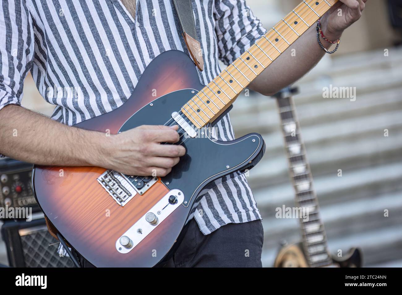 Gros plan des mains d'un musicien jouant de la guitare lors d'une performance en direct à la lumière du jour. Banque D'Images